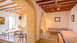 A room with a bed, a dining table with chairs, and a ceiling fan. - Embat alberg juvenil - Hostel (Montuiri)