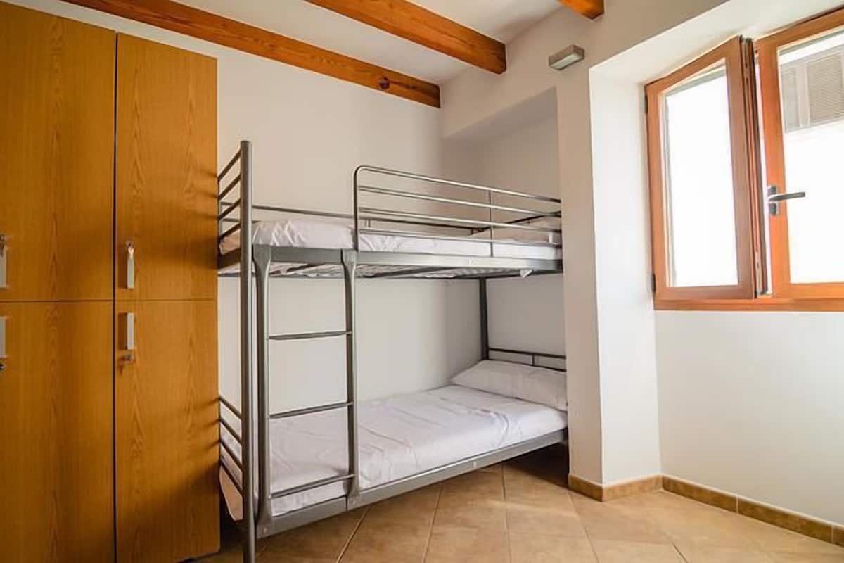 Habitación con literas, armarios de madera y una ventana.