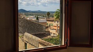 A window with a view of a town with buildings and mountains in the distance. - Embat alberg juvenil - Hostel (Montuiri)