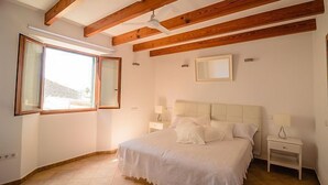 A bedroom with a large bed, wooden beams, a ceiling fan, and a window with a view. - Embat alberg juvenil - Hostel (Montuiri)