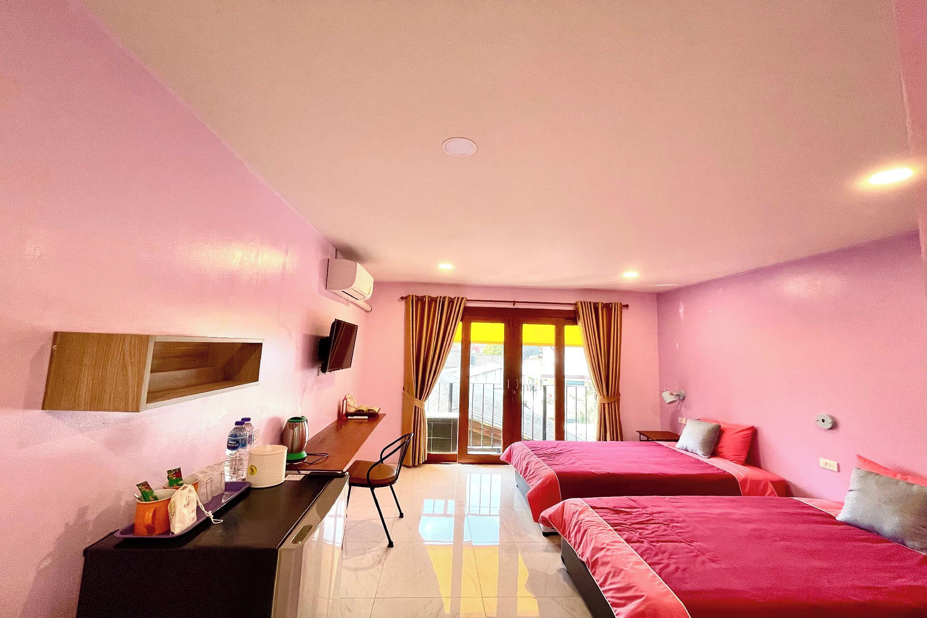 A hotel room with two beds, a desk, a chair, and a TV.