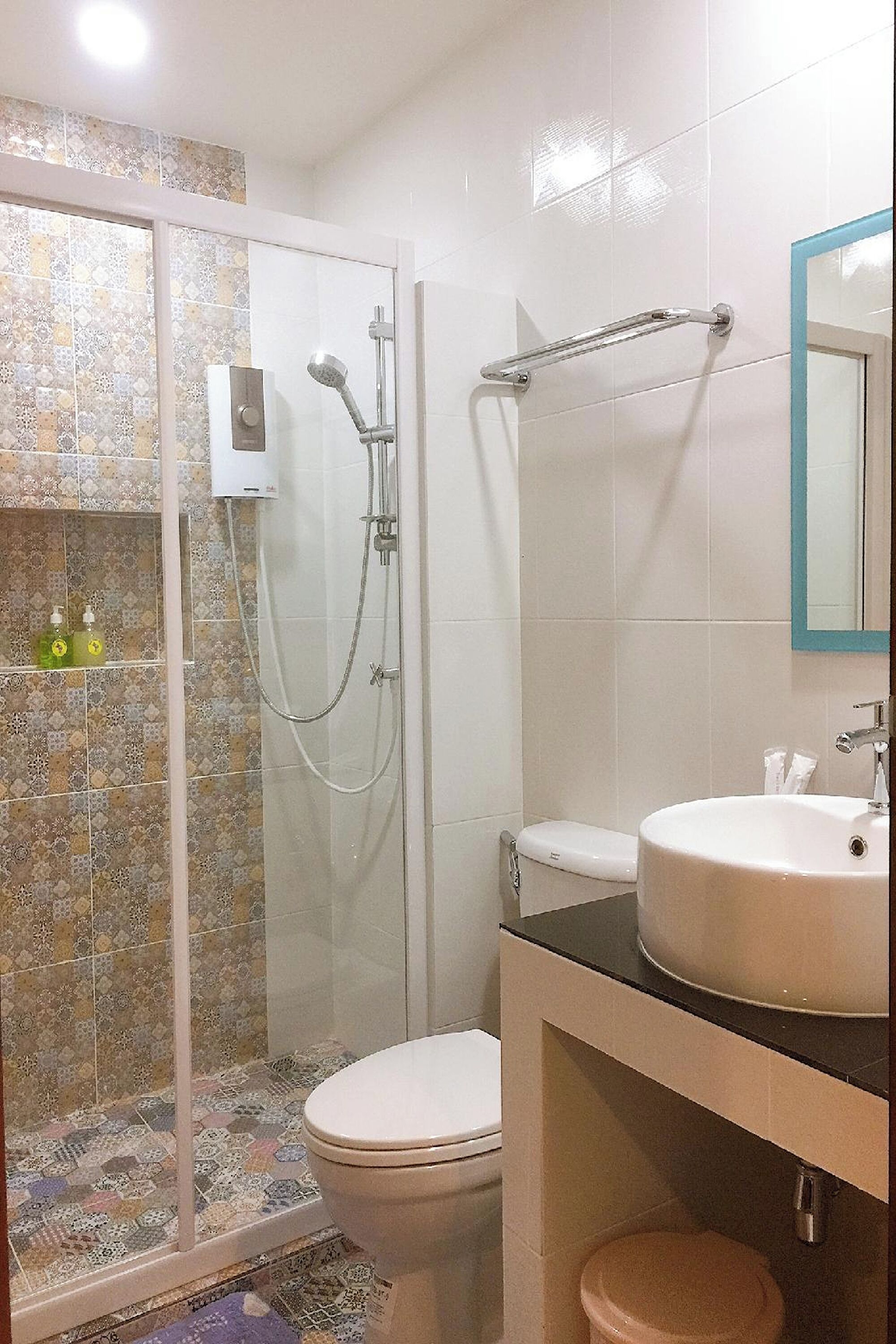 A bathroom with a glass-enclosed shower, a toilet, and a sink with a mirror above it.