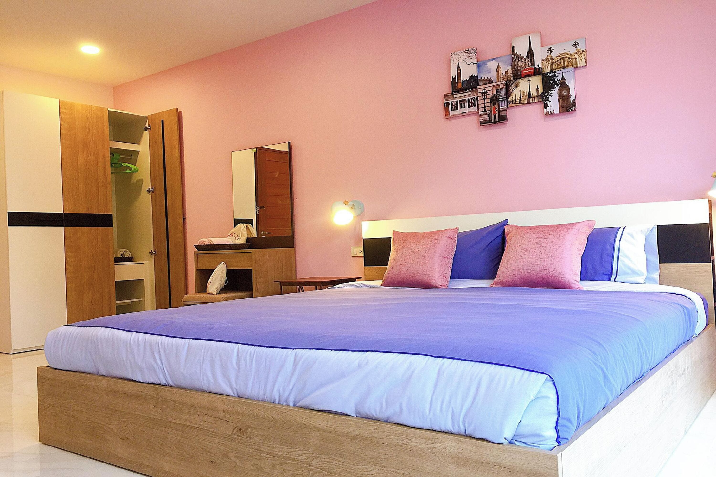 A bedroom with a bed, a wardrobe, a bedside table, and a wall with pictures.