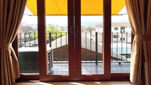 A room with a large sliding glass door leading to a balcony with a view of the cityscape.