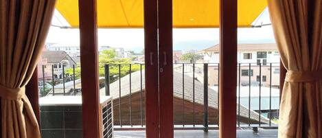 A room with a large sliding glass door leading to a balcony with a view of the cityscape.