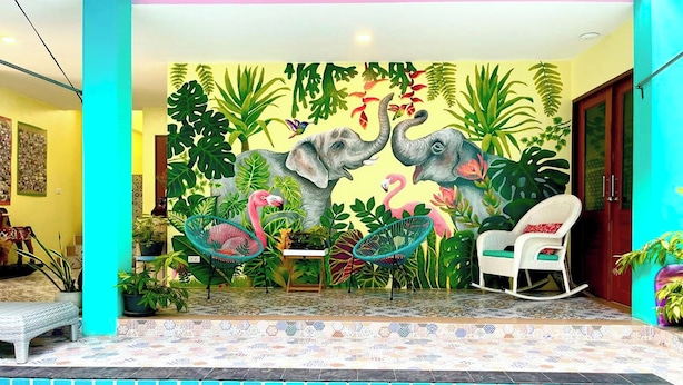 A pool area with a mural of elephants, flamingos, and tropical plants.