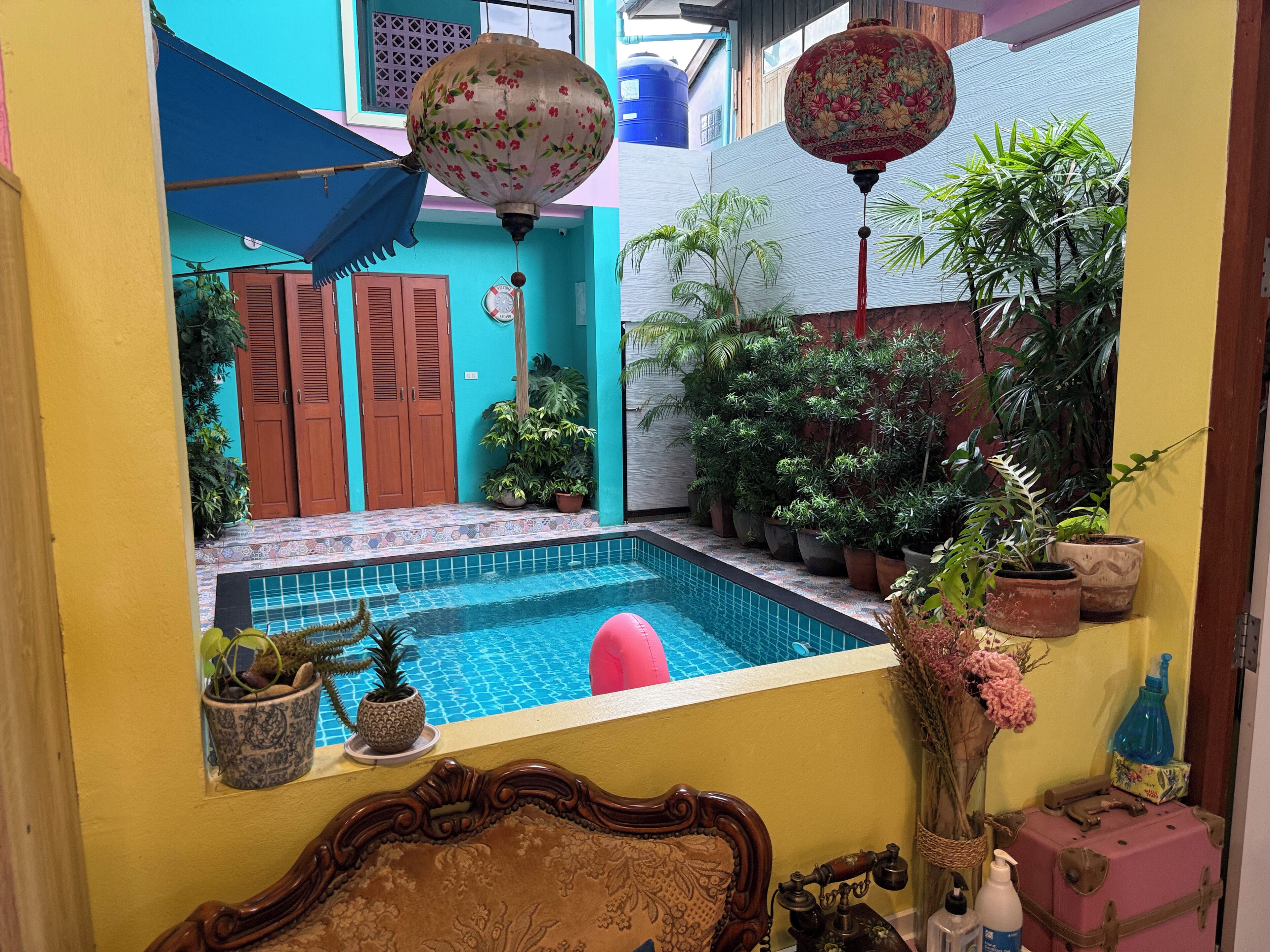 A small courtyard with a pool, potted plants, and traditional decor.