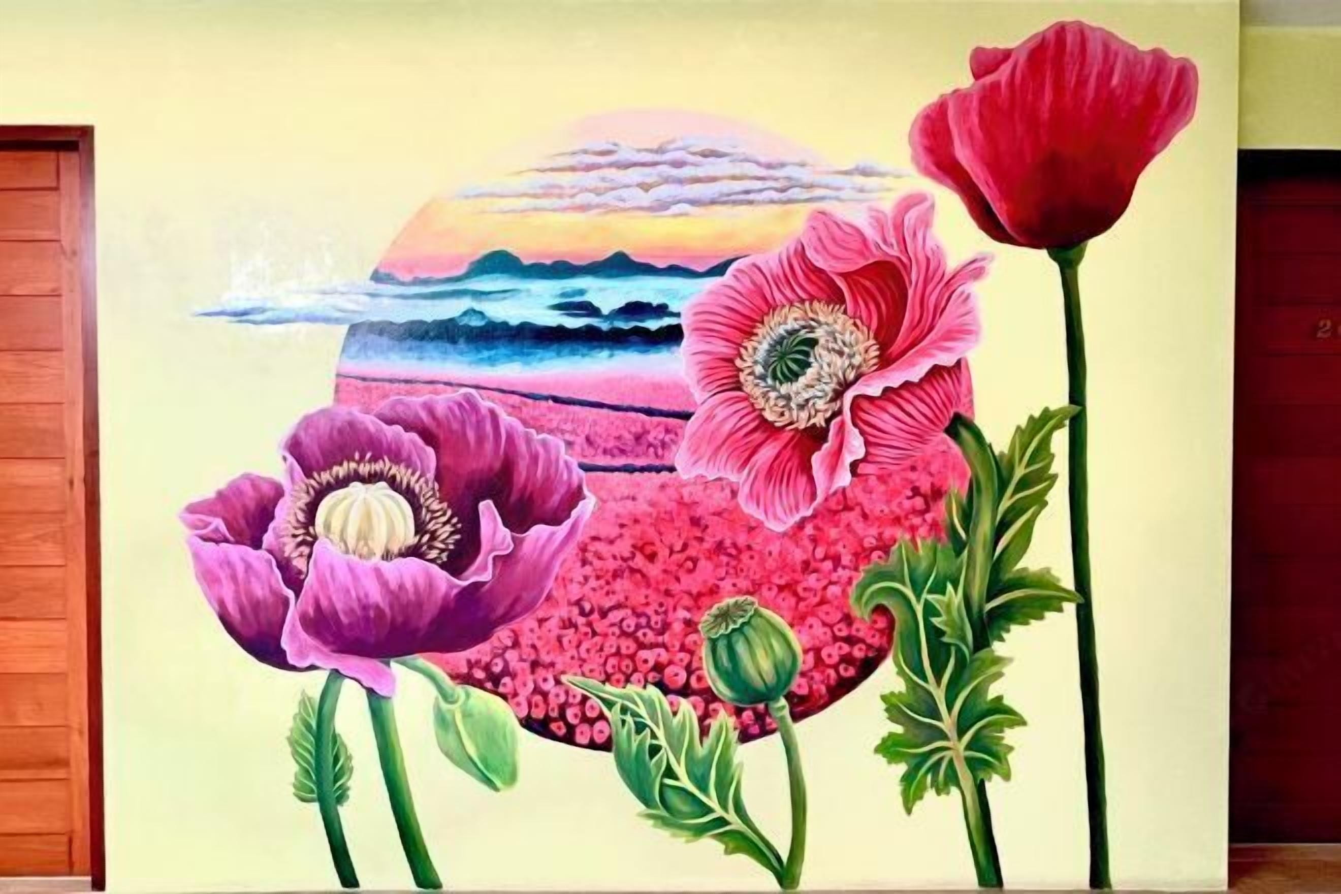 Une fresque représentant de grandes fleurs et un coucher de soleil sur l’océan.
