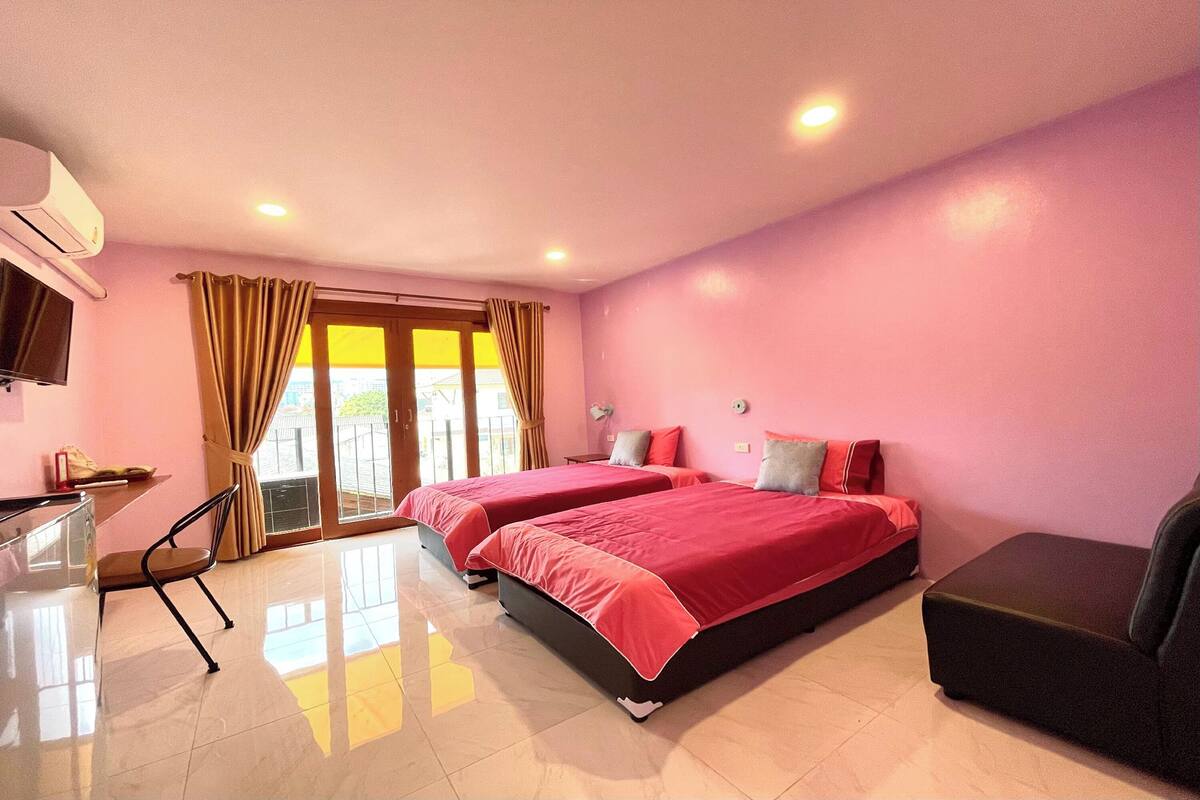 Une chambre d’hôtel avec deux lits, un bureau, une chaise et un canapé.