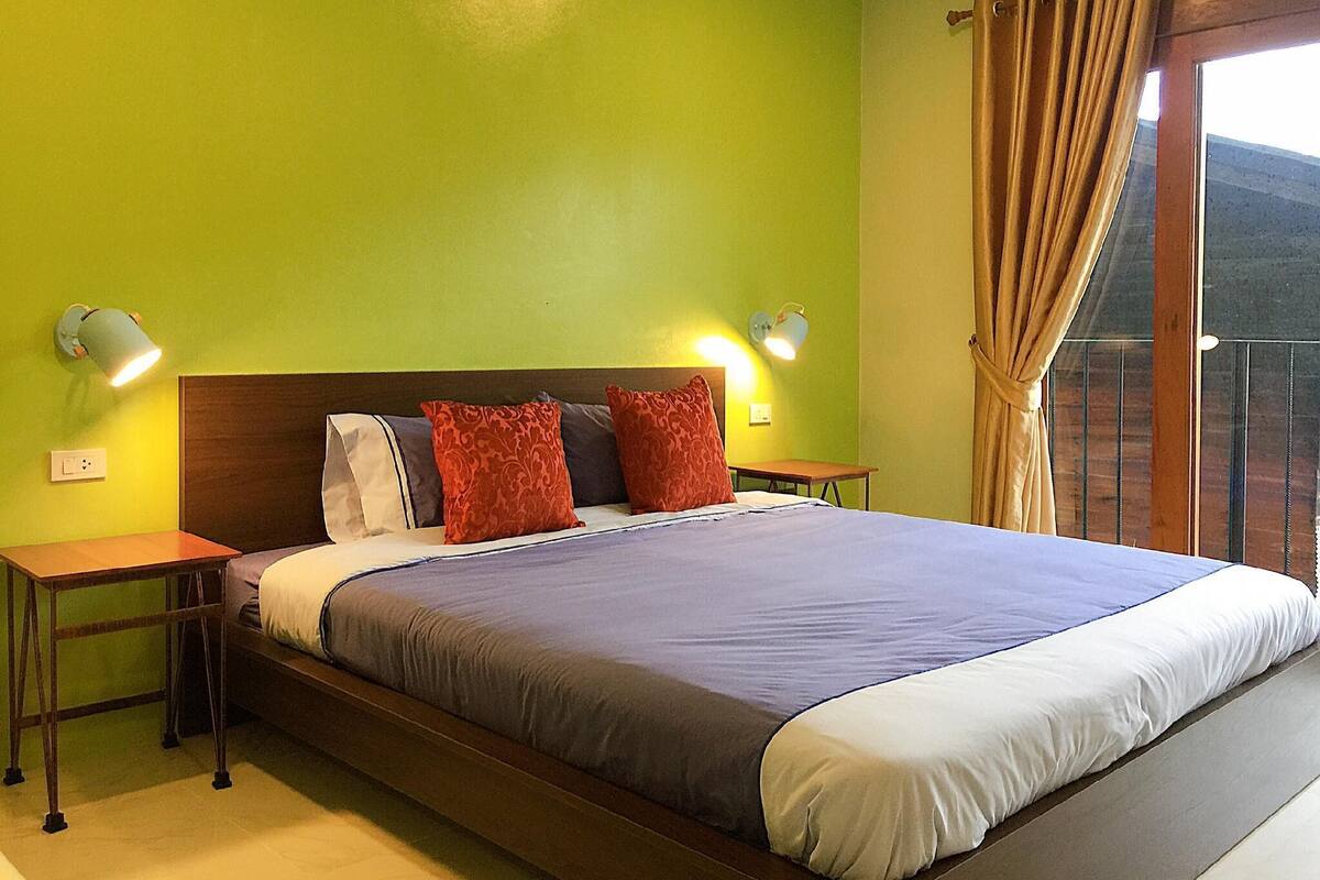 Une chambre à coucher avec un grand lit, deux tables de chevet et deux lampes fixées au mur.
