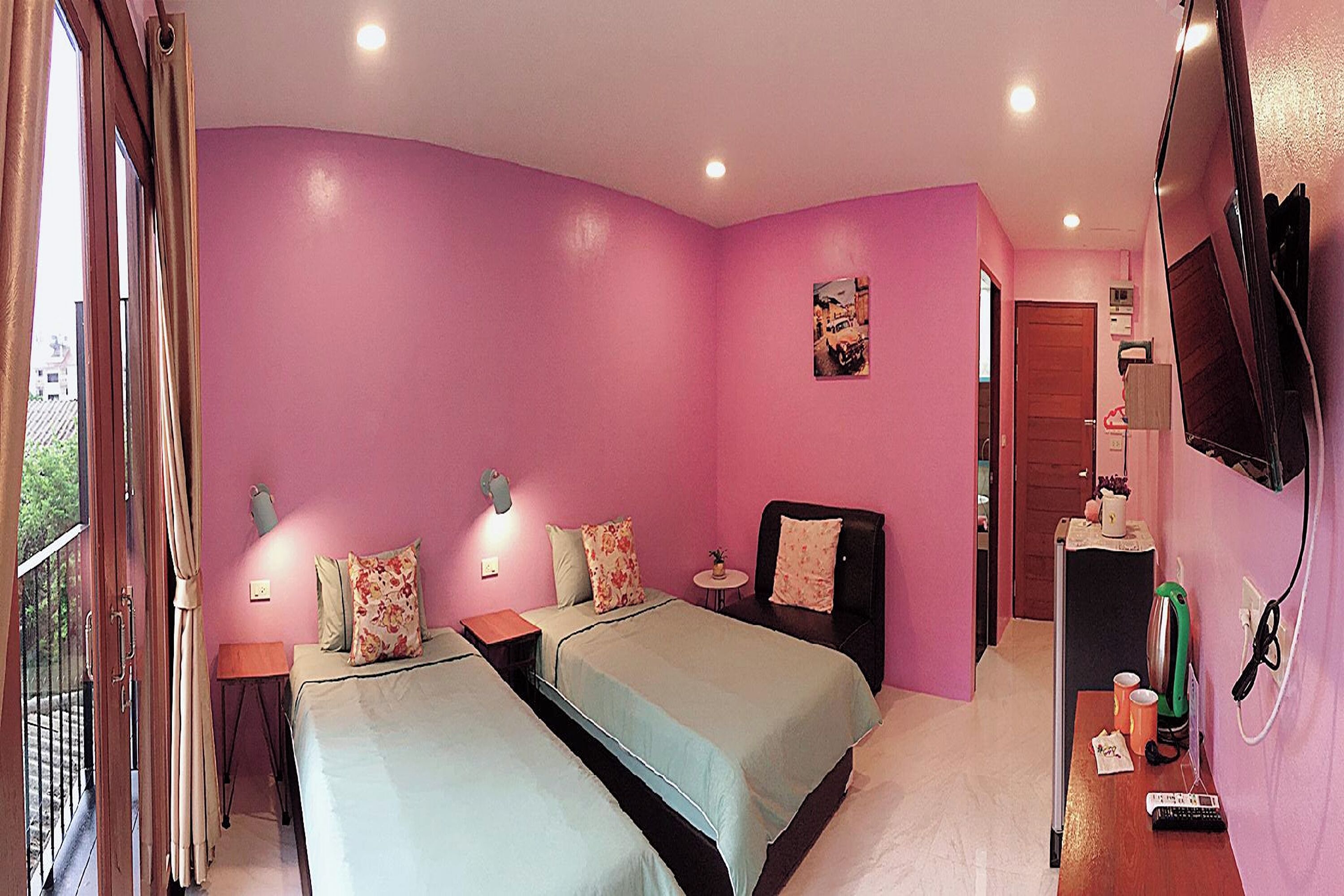 A room with two beds, a small table, a TV, and a window with curtains.
