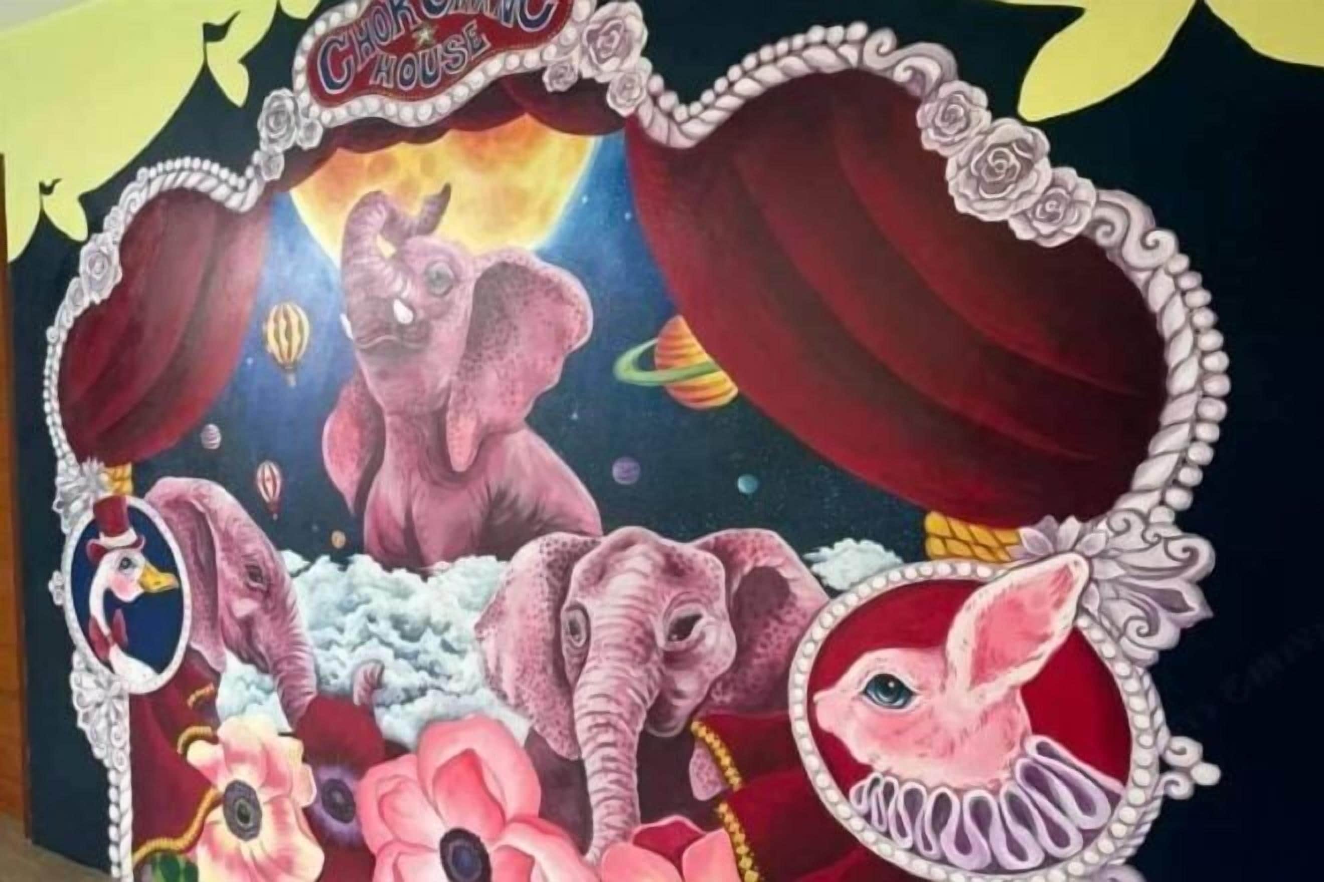 A vibrant mural with elephants and flowers, framed by a decorative border.