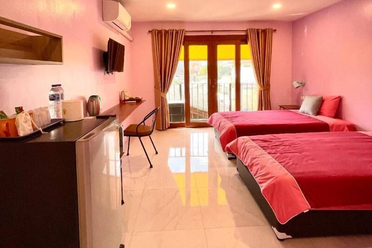 Une chambre d’hôtel avec un lit, un bureau, une chaise, une télévision et une fenêtre avec des rideaux.