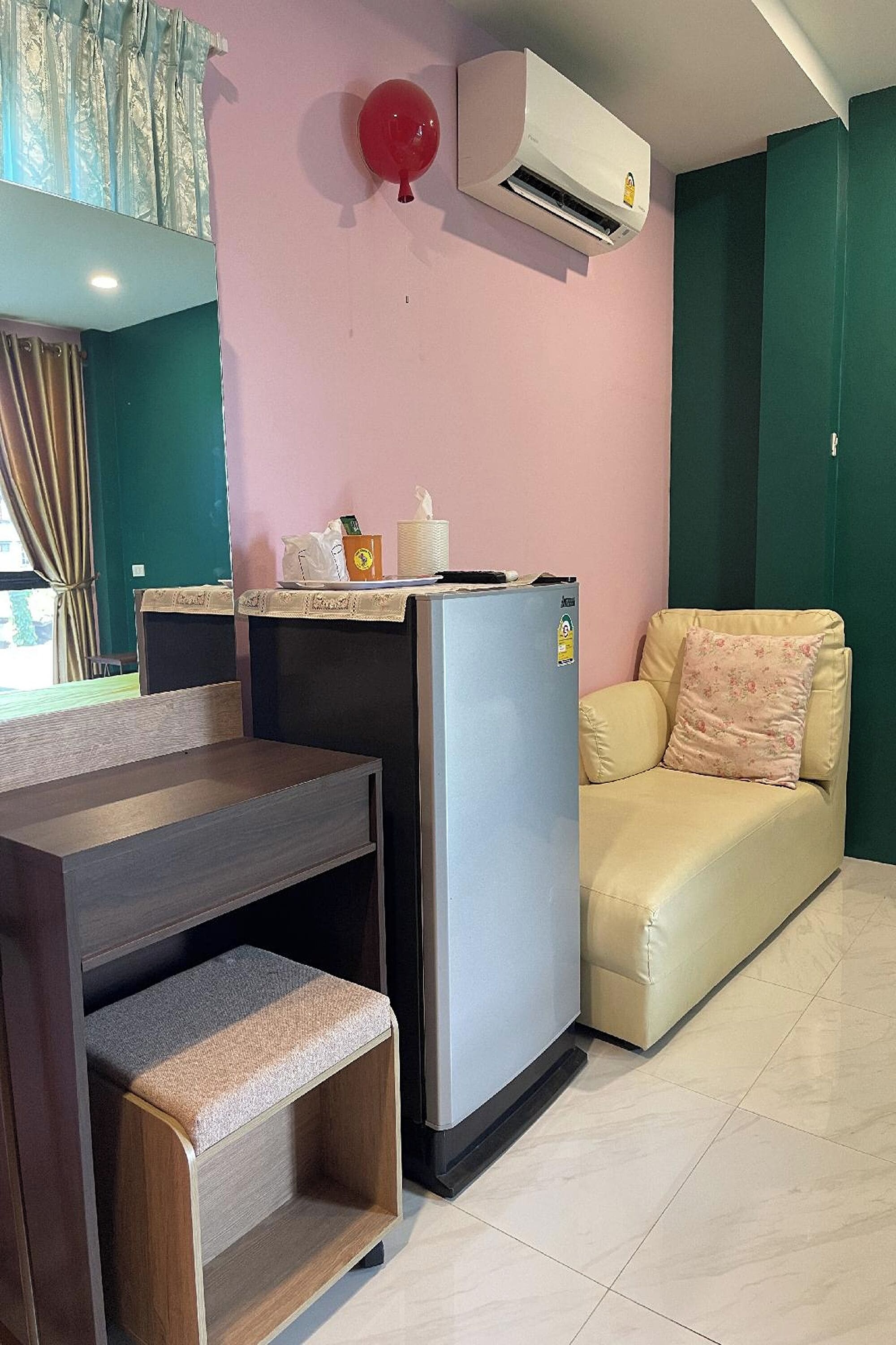A compact living space with a kitchenette, a sofa, a small table, and a bench.