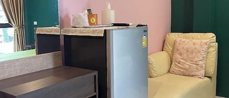 A compact living space with a kitchenette, a sofa, a small table, and a bench.