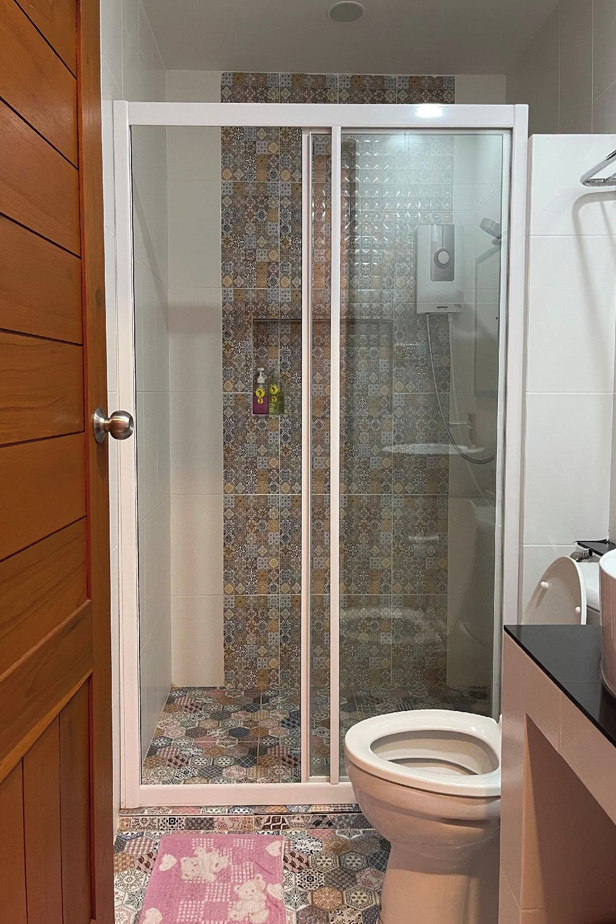 A bathroom with a shower enclosure, a toilet, and a sink.