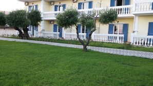A multi-story building with balconies, a tiled border, and a well-maintained lawn. - Elaias Gi Residence (Kefalonia)
