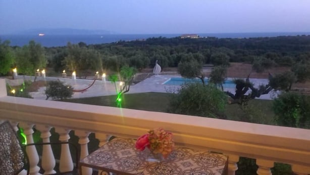 A balcony with a view of a landscaped garden and a pool. - Elaias Gi Residence (Kefalonia)