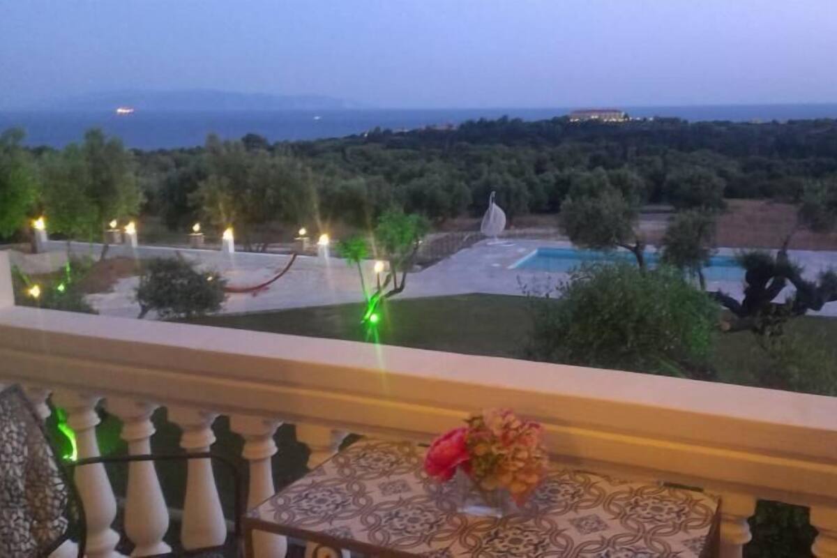 A balcony with a view of a landscaped garden and a pool.