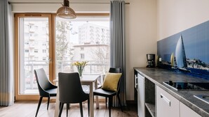 Una cocina moderna con comedor, ventanas grandes con cortinas y vista panorámica de la ciudad.