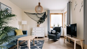 Una sala moderna con sofá, mesa de centro, televisor y plantas decorativas.