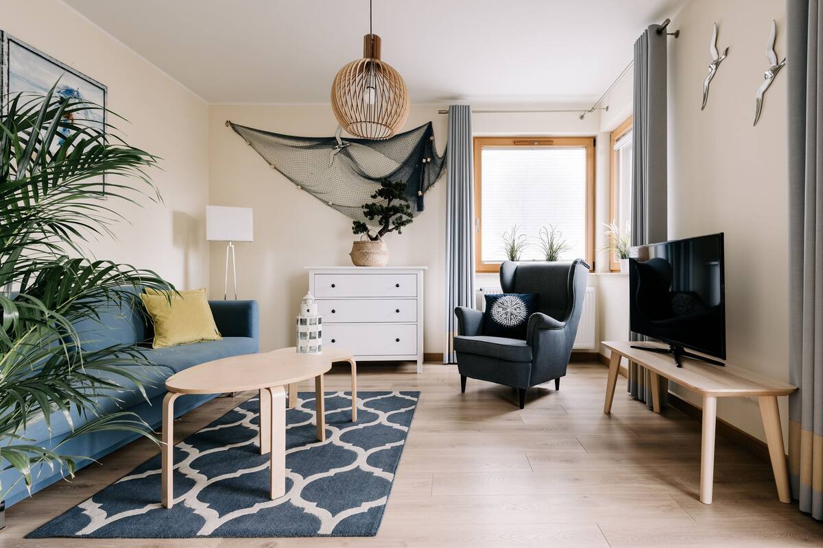 A modern living room with a sofa, coffee table, TV, and decorative plants.