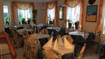 A restaurant with round tables, chairs, and potted plants.