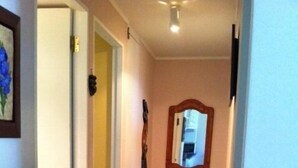 A hallway with a wooden door, a mirror, and a mat on the floor. - Departamento Modulo Alto Mirasol 2 (Algarrobo)