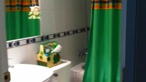 A bathroom with a toilet, sink, and shower curtain. - Departamento Modulo Alto Mirasol 2 (Algarrobo)