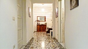Un pasillo con suelo de baldosas que conduce a una habitación con un armario de madera y una silla.