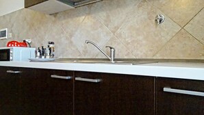 Una cocina moderna con un lavamanos de acero inoxidable, armarios oscuros y salpicadero de azulejos.