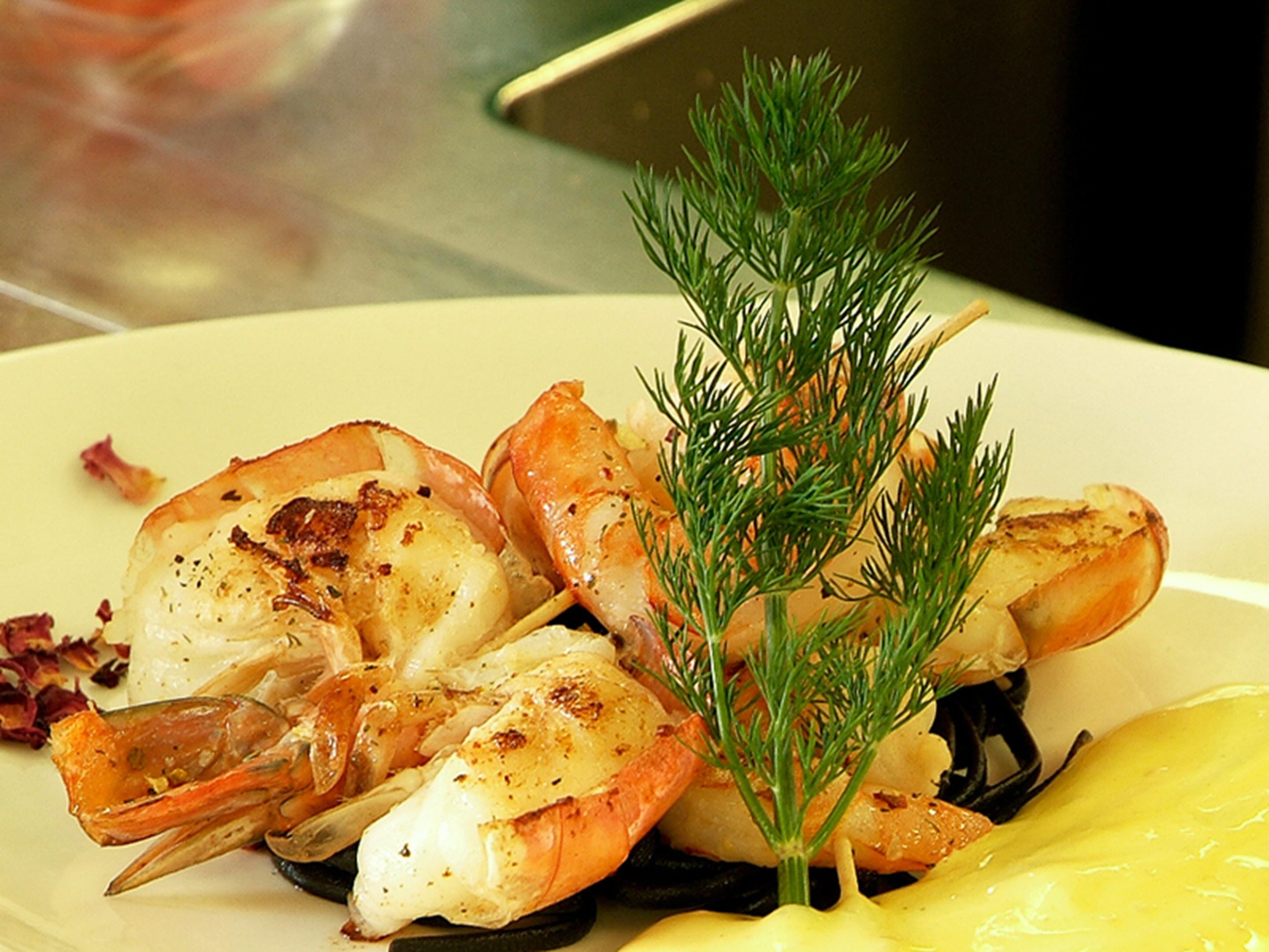 A plate of grilled shrimp and scallops garnished with dill.