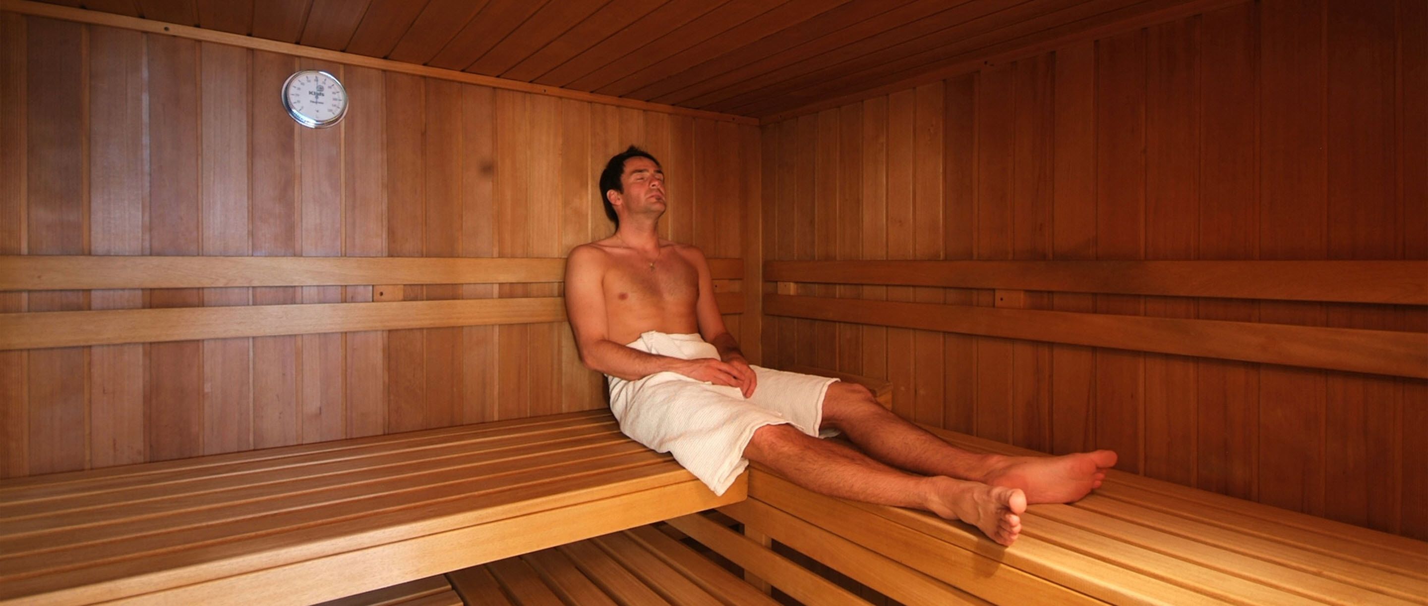 Sauna, jossa on puiset lauteet ja seinällä n äkyvä lämpömittari.
