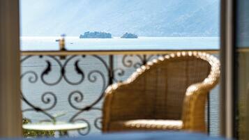 A wicker chair with a view of a calm sea and distant land.