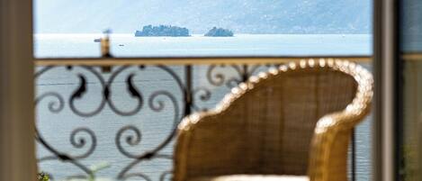 A wicker chair with a view of a calm sea and distant land.
