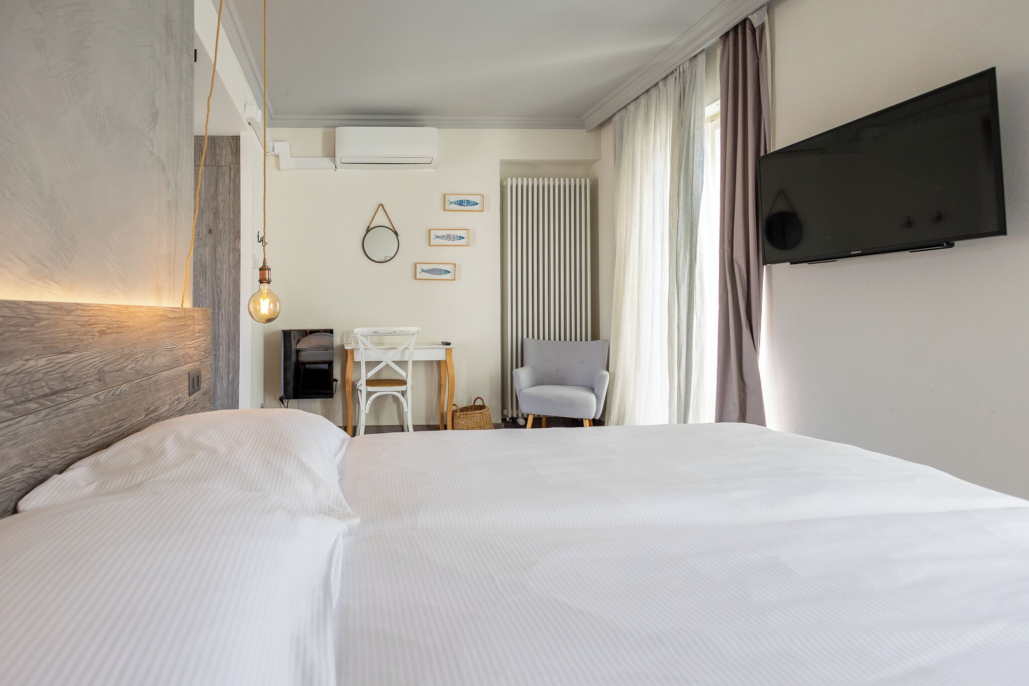 Een hotelkamer met een groot bed, een bureau, een stoel, een televisie en een raam met gordijnen.