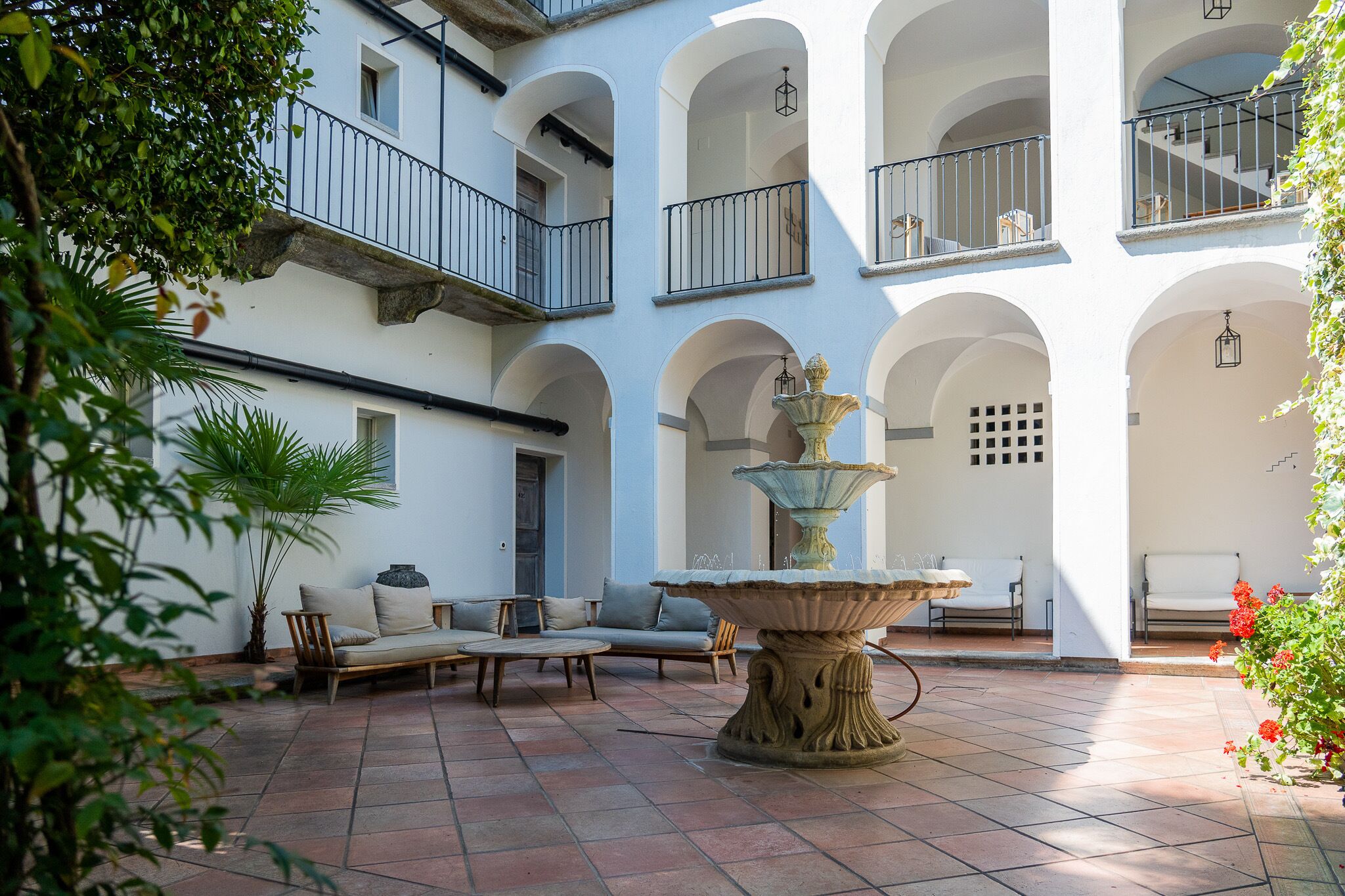 A courtyard with a fountain, outdoor seating, and a building with multiple balconies.