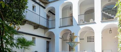 A courtyard with a fountain, outdoor seating, and a building with multiple balconies.