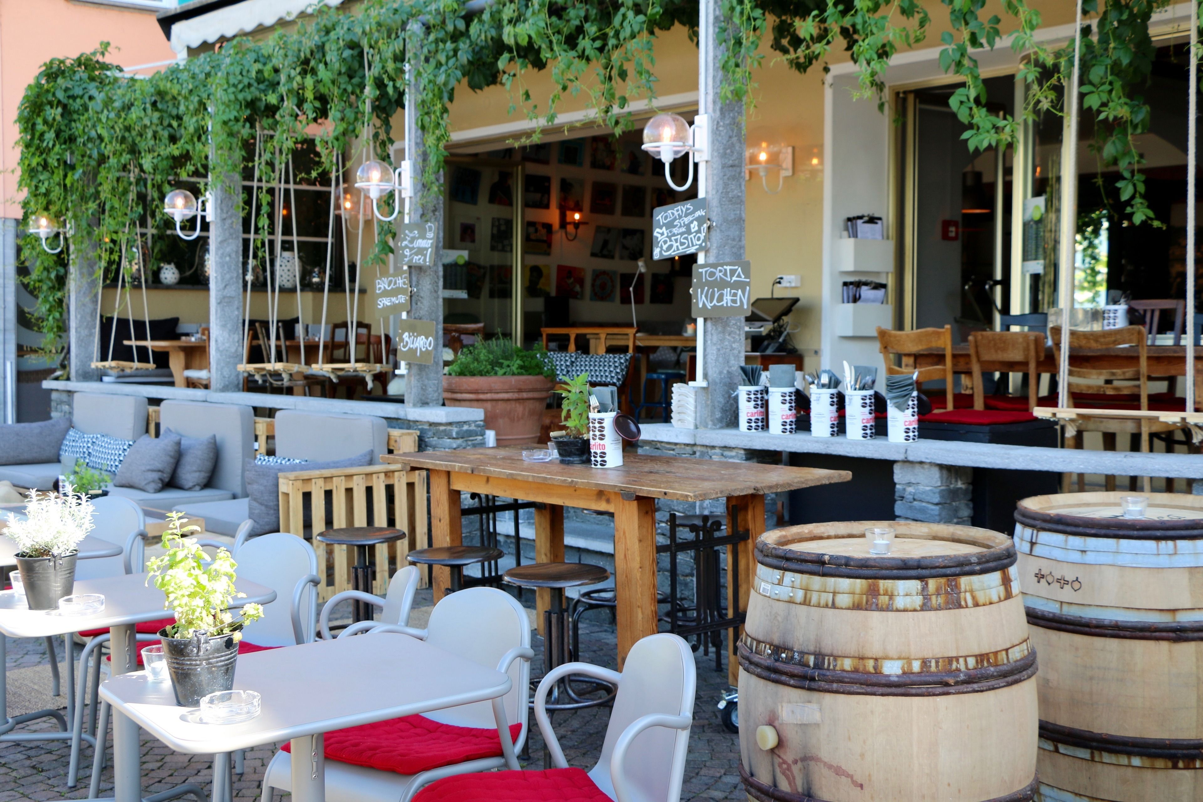 Un espace extérieur aménagé avec des tables et des chaises, des plantes en pot et des barils en bois.