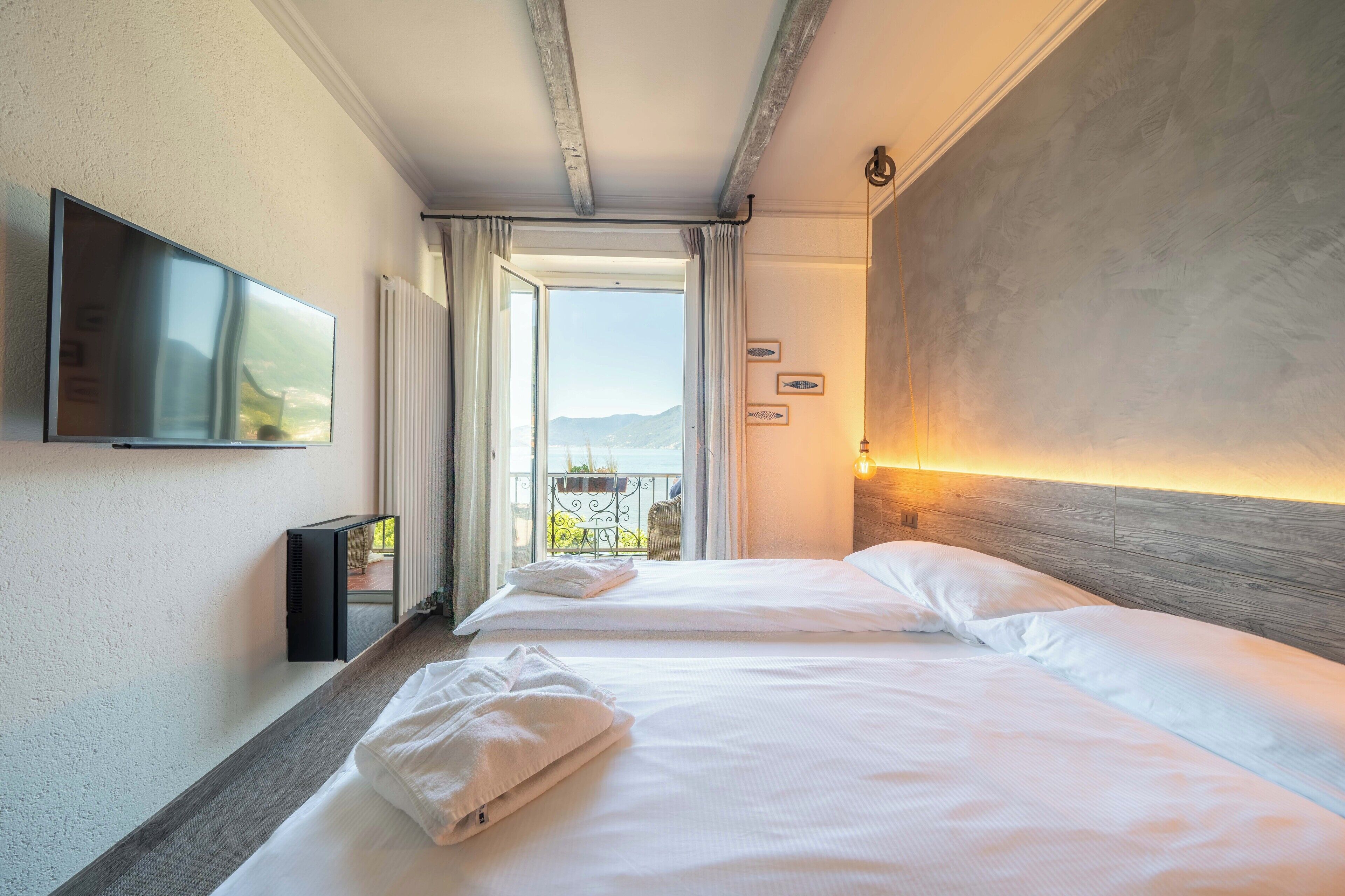 A hotel room with two beds, a TV, and a view of the outdoors.