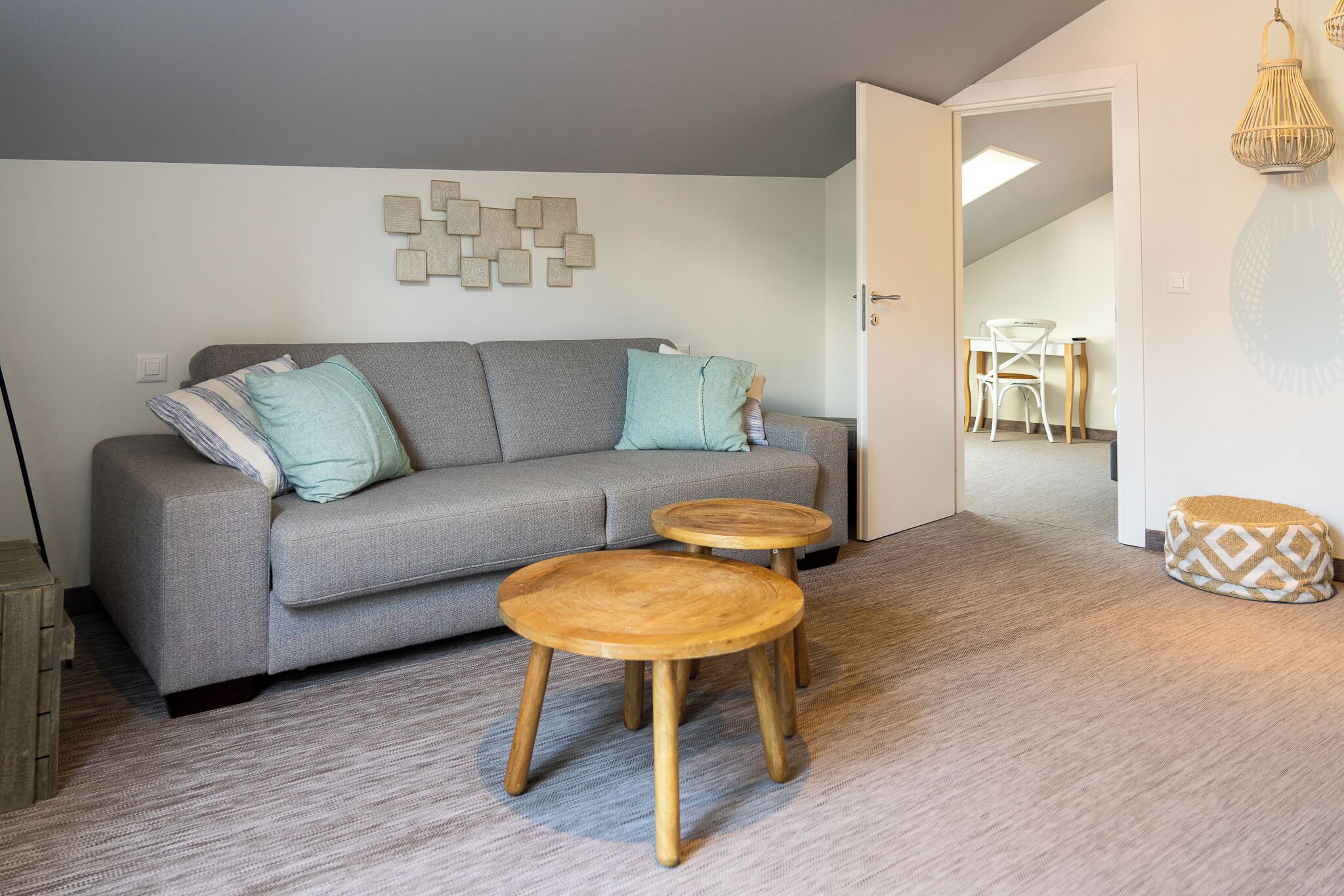 A modern living room with a grey sofa, two wooden side tables, and a patterned rug.