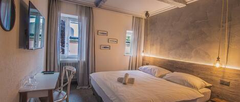 A hotel room with a bed, a desk, a chair, and a window with curtains.