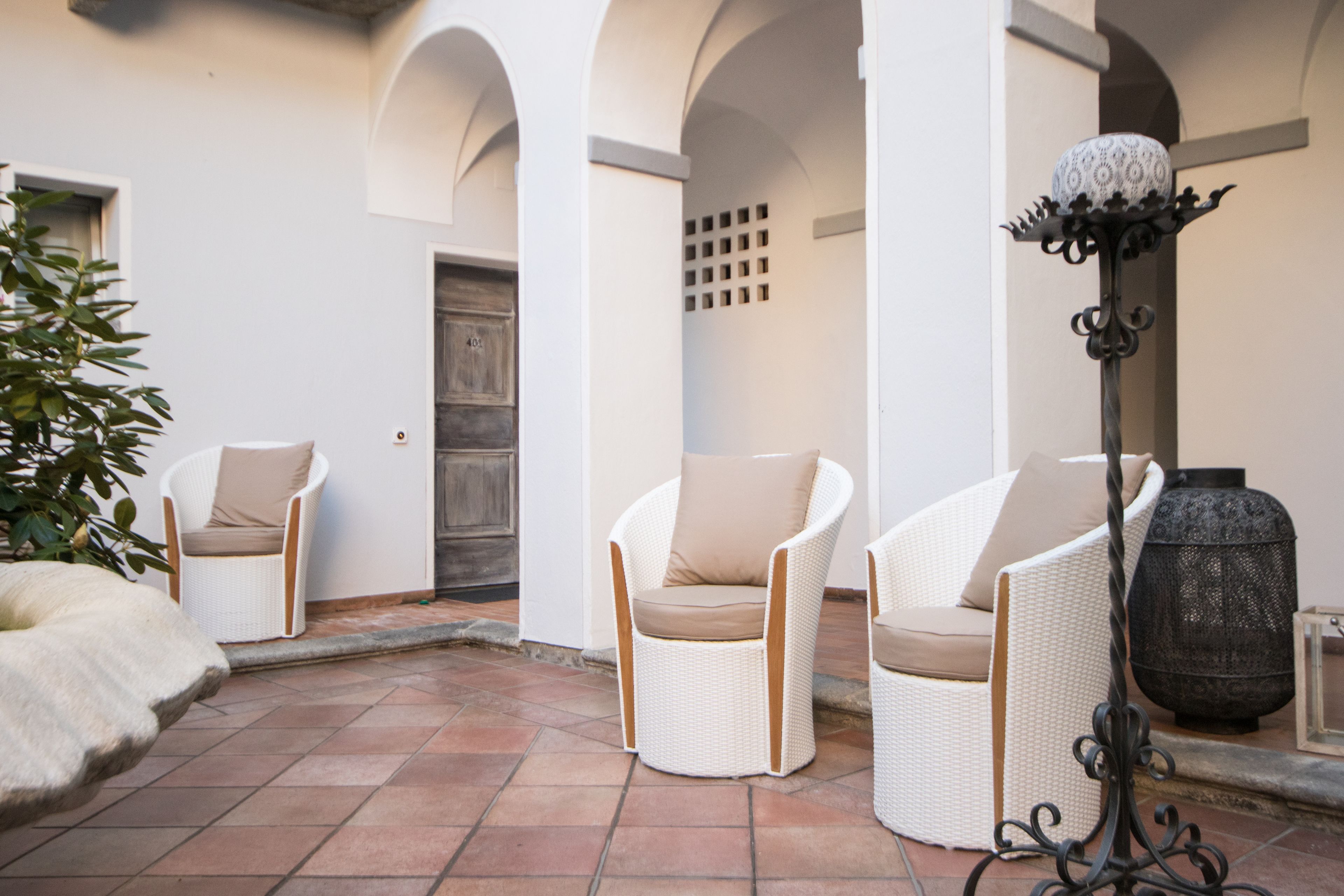 A patio area with white wicker chairs and a large decorative vase.