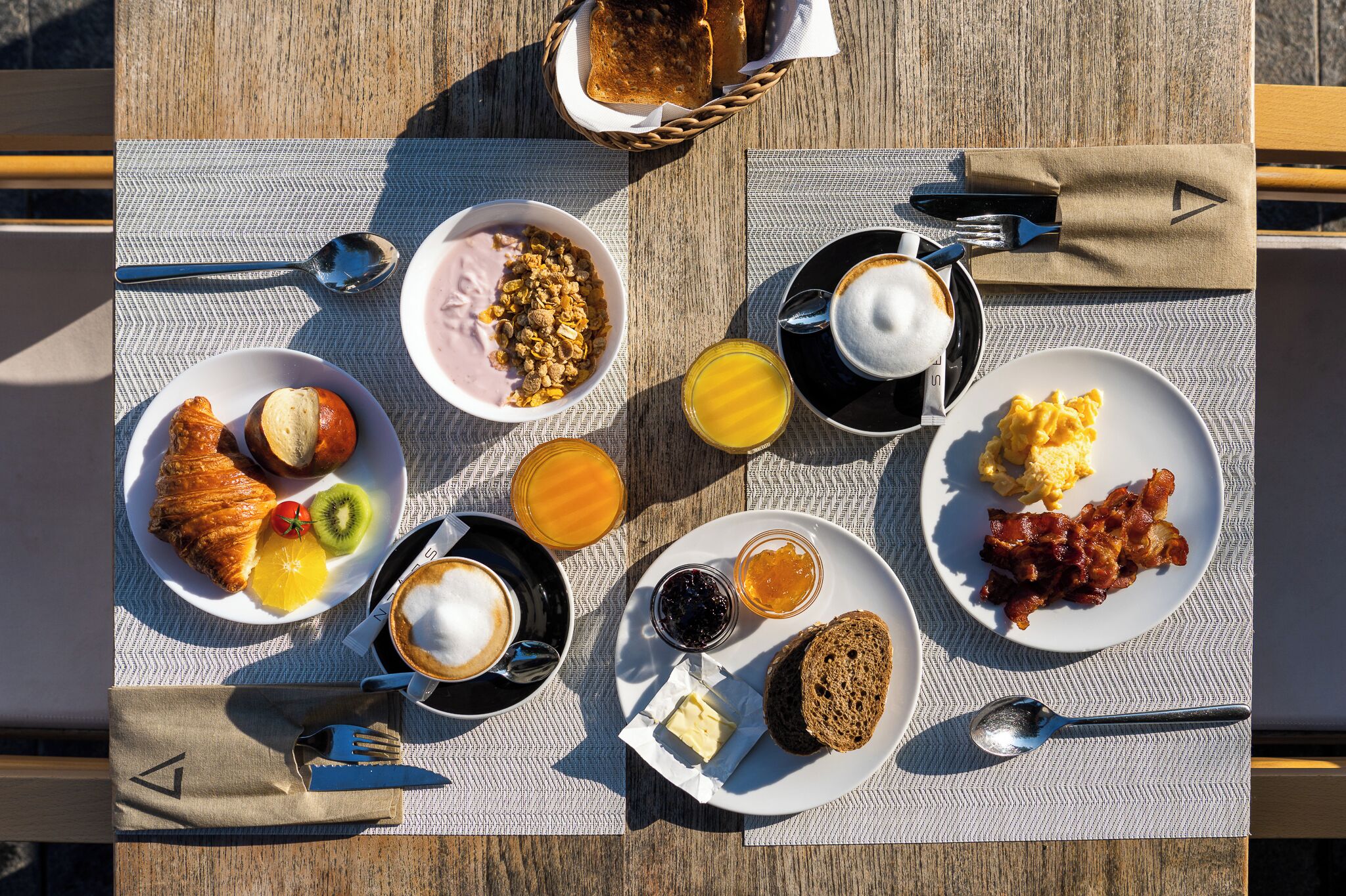 A breakfast setting with croissants, fruits, coffee, and various spreads on a table.