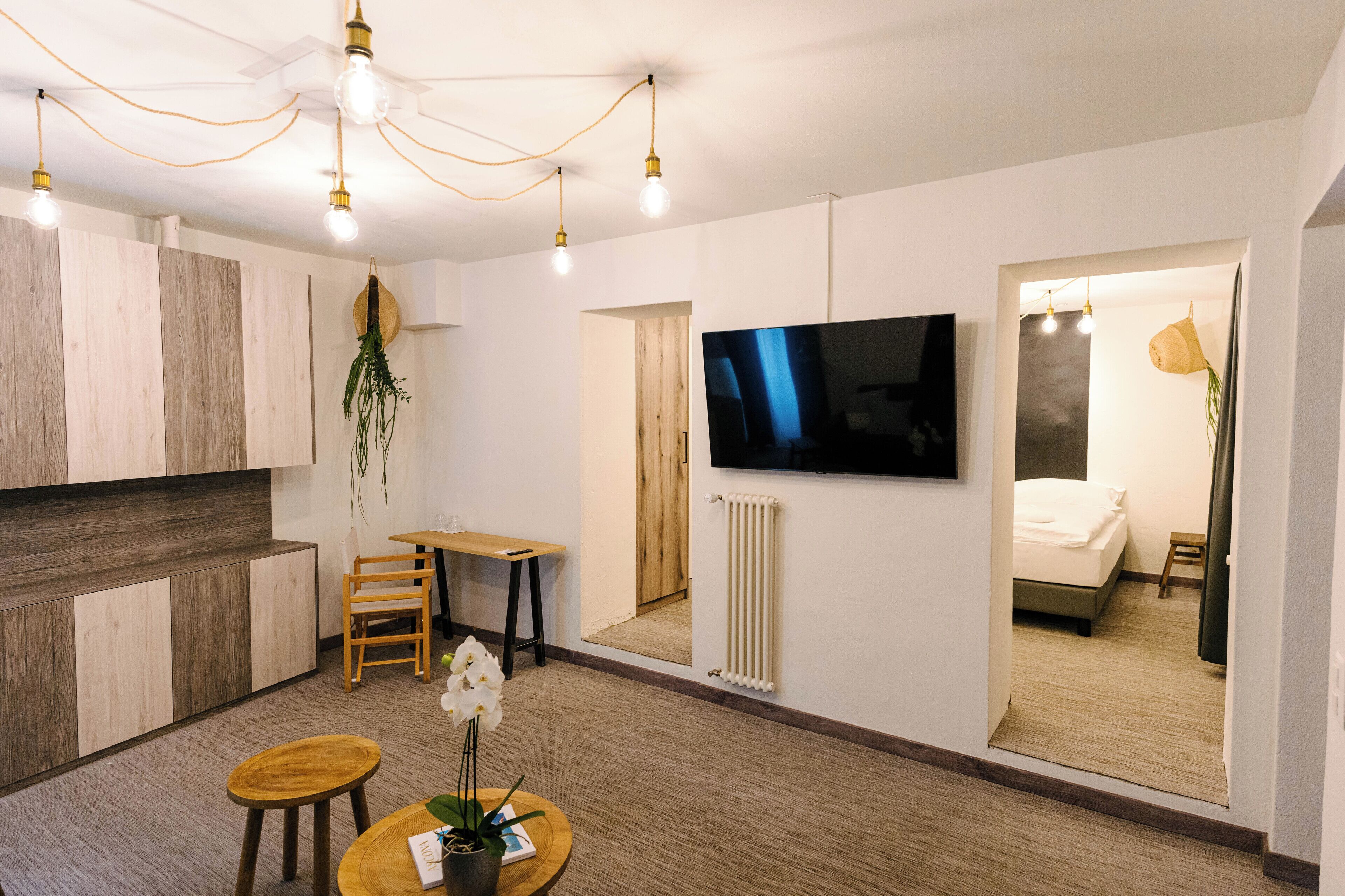 Una sala de estar moderna con un televisor de pantalla plana, muebles de madera y un espejo grande que refleja la habitación.