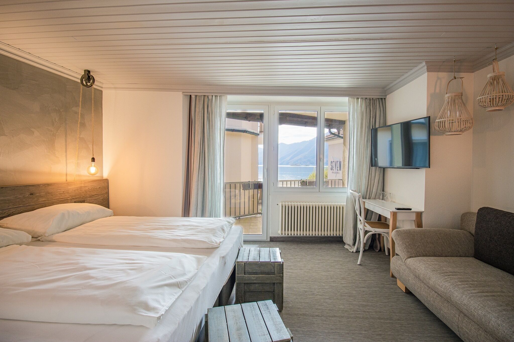 Ein Hotelzimmer mit Bett, Schreibtisch, Sofa und Fernseher.