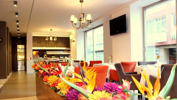 A hotel lobby with a long reception desk, modern decor, and a view of the kitchen area. - Hotel Le Maritime (Istanbul)