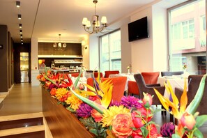 A hotel lobby with a long reception desk, modern decor, and a view of the kitchen area. - Hotel Le Maritime (Istanbul)