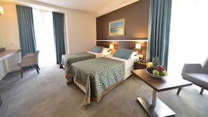 A hotel room with two beds, a desk, a chair, and a fruit bowl. - Hotel Le Maritime (Istanbul)