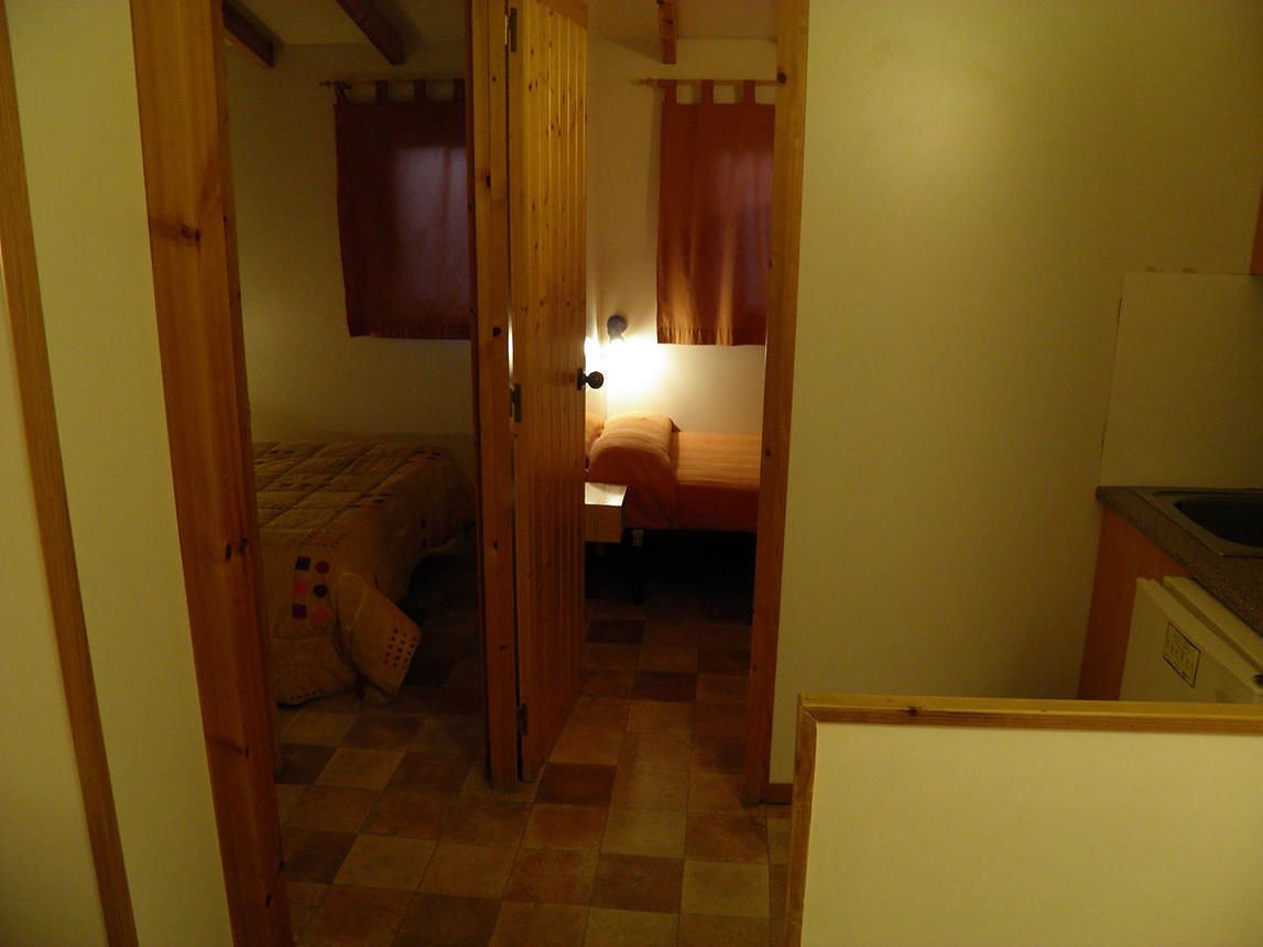 Un pasillo estrecho que conduce a un dormitorio con una cama y un ventanal pequeño.